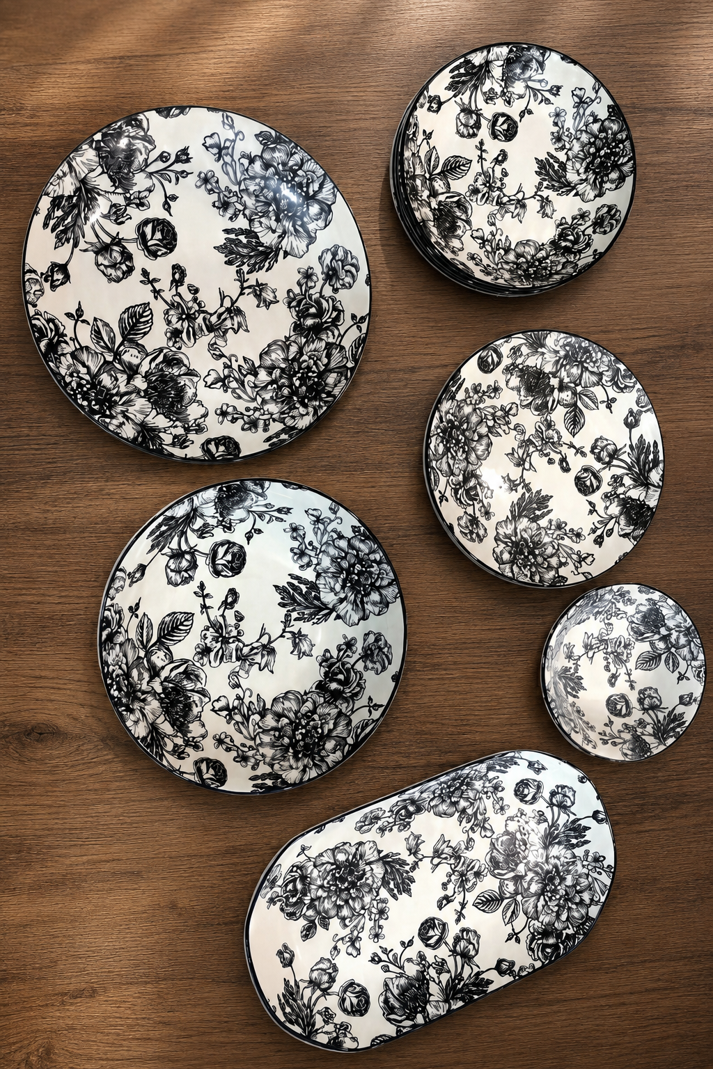 28-Piece Black Floral Porcelain Dinnerware Set laid out on a wooden surface